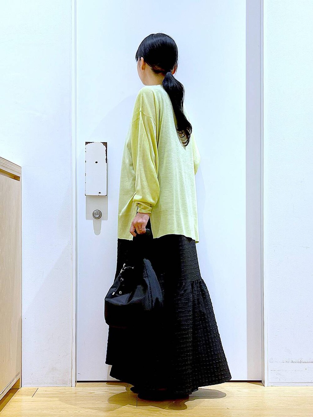 ブラック系のワンピース、グリーン系のカーディガン/ボレロ、ブラック系のショルダーバッグを着用したレディースの春コーディネートの3枚目の写真