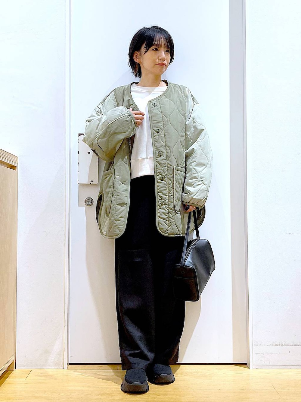 ブラック系のショルダーバッグ、ホワイト系のスウェット、ブラック系のブーツを着用したレディースの秋コーディネートの2枚目の写真