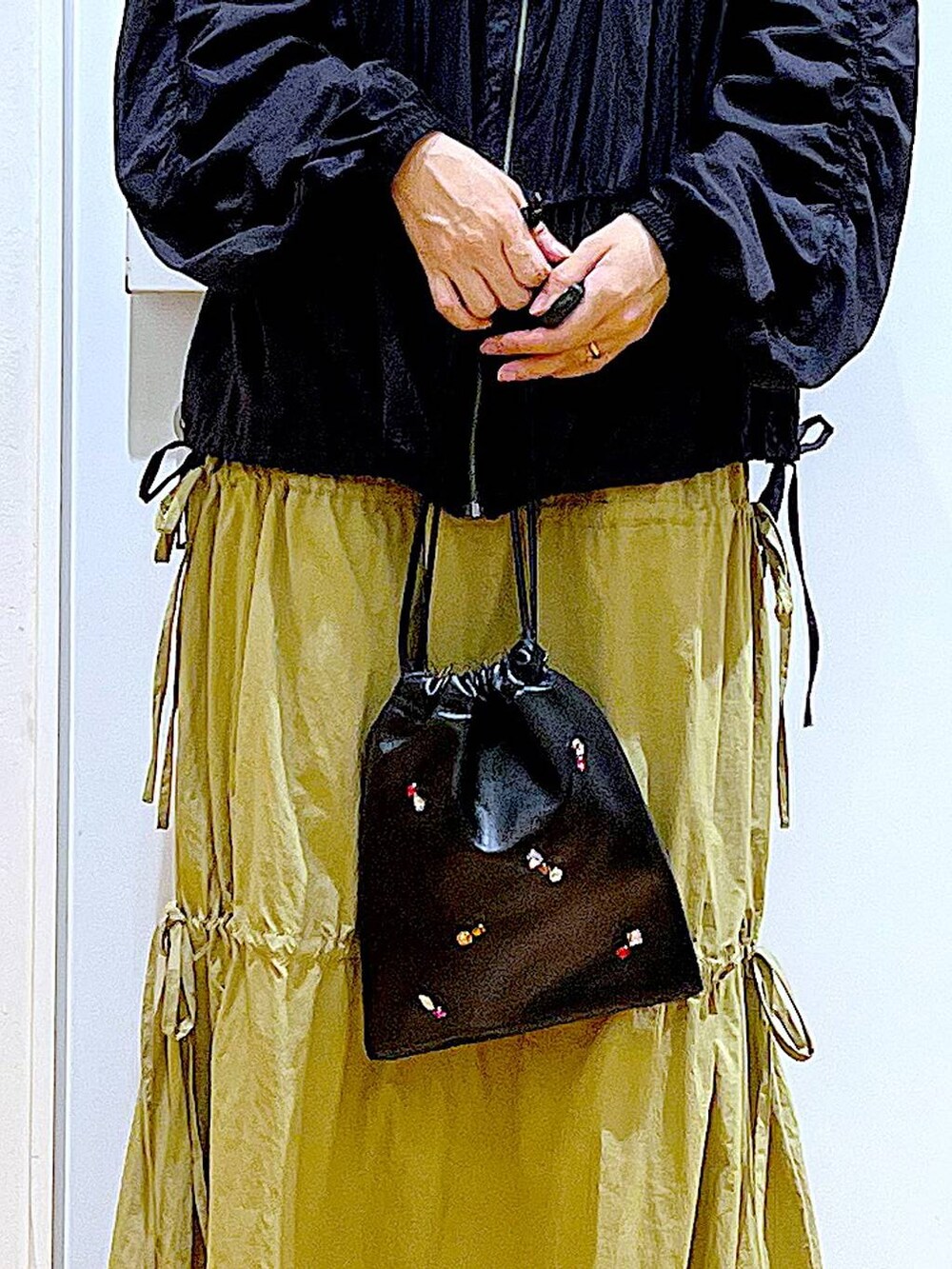 ブラック系のショルダーバッグ、ブラック系のローファー、イエロー系のスカートを着用したレディースの秋コーディネートの9枚目の写真