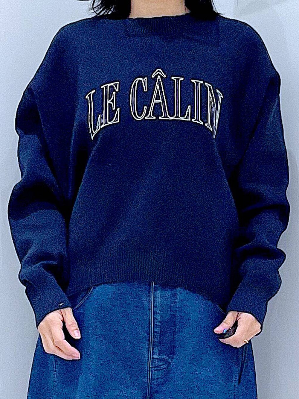 グリーン系のトートバッグ、ブルー系のニット/セーター、ブルー系のデニムパンツを着用したレディースの冬コーディネートの7枚目の写真