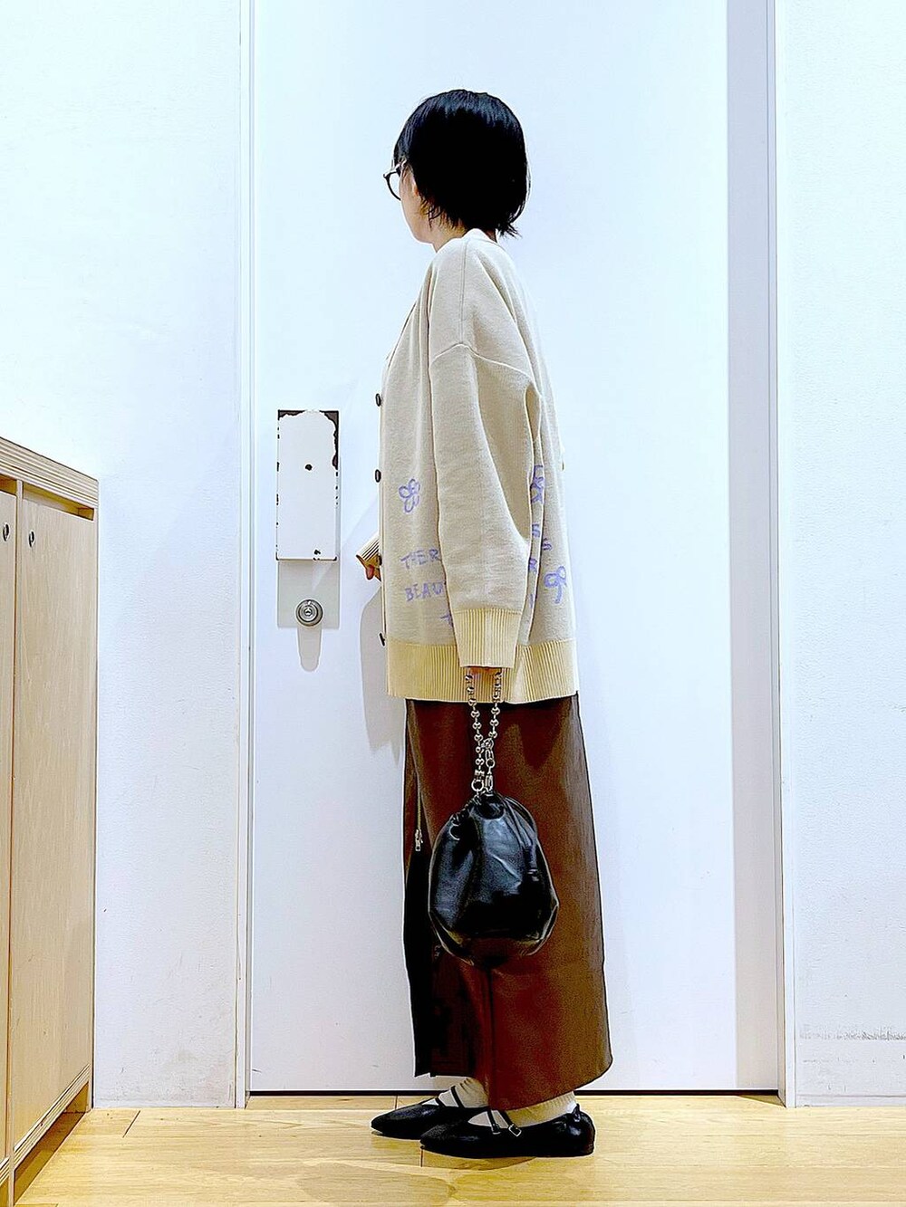 ブラウン系のスカート、ブラック系のショルダーバッグ、ブラック系のパンプスを着用したレディースの秋コーディネートの3枚目の写真