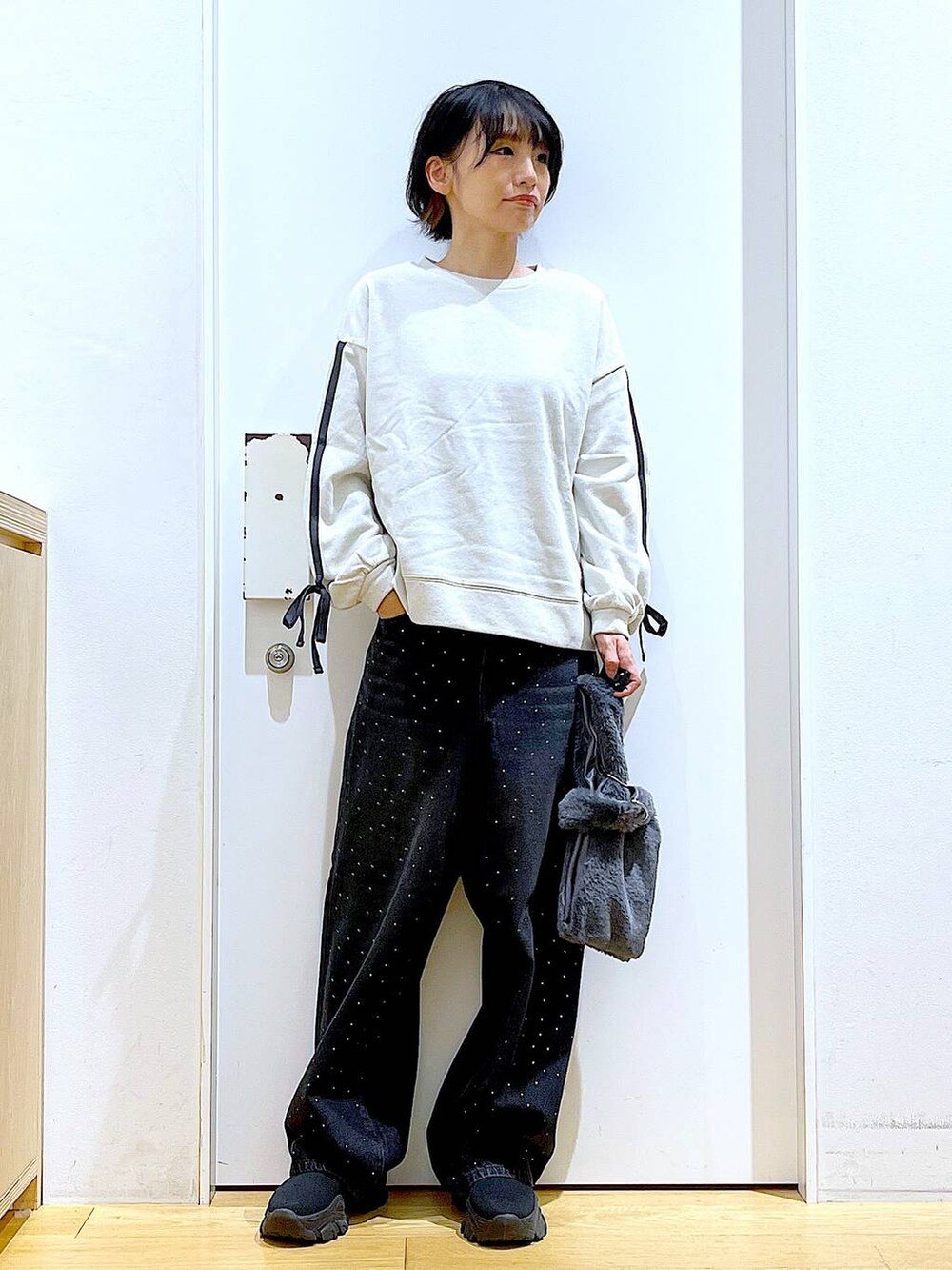 グレー系のショルダーバッグ、ブラック系のブーツ、ベージュ系のスウェットを着用したレディースの秋コーディネートの2枚目の写真