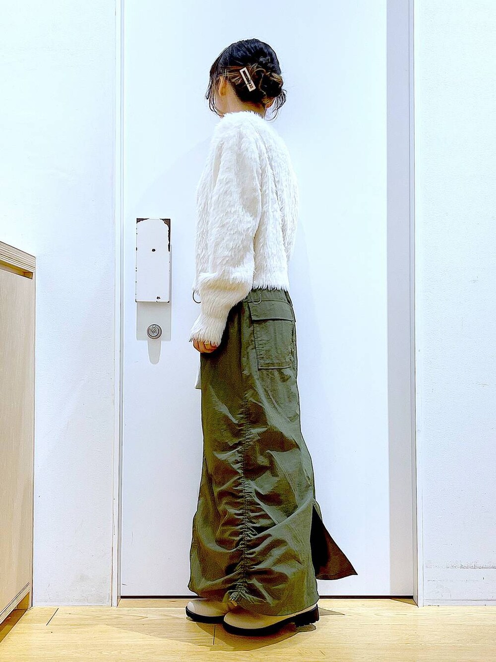 ベージュ系のブーツ、ベージュ系のニット/セーター、グリーン系のスカートを着用したレディースの冬コーディネートの3枚目の写真