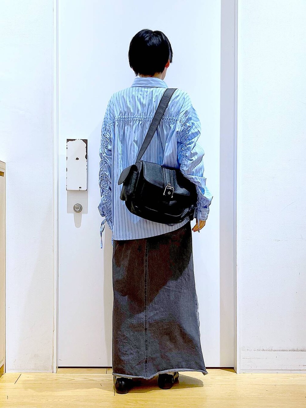 ブラック系のパンプス、ブラック系のデニムスカート、ブラック系のショルダーバッグを着用したレディースの春コーディネートの5枚目の写真
