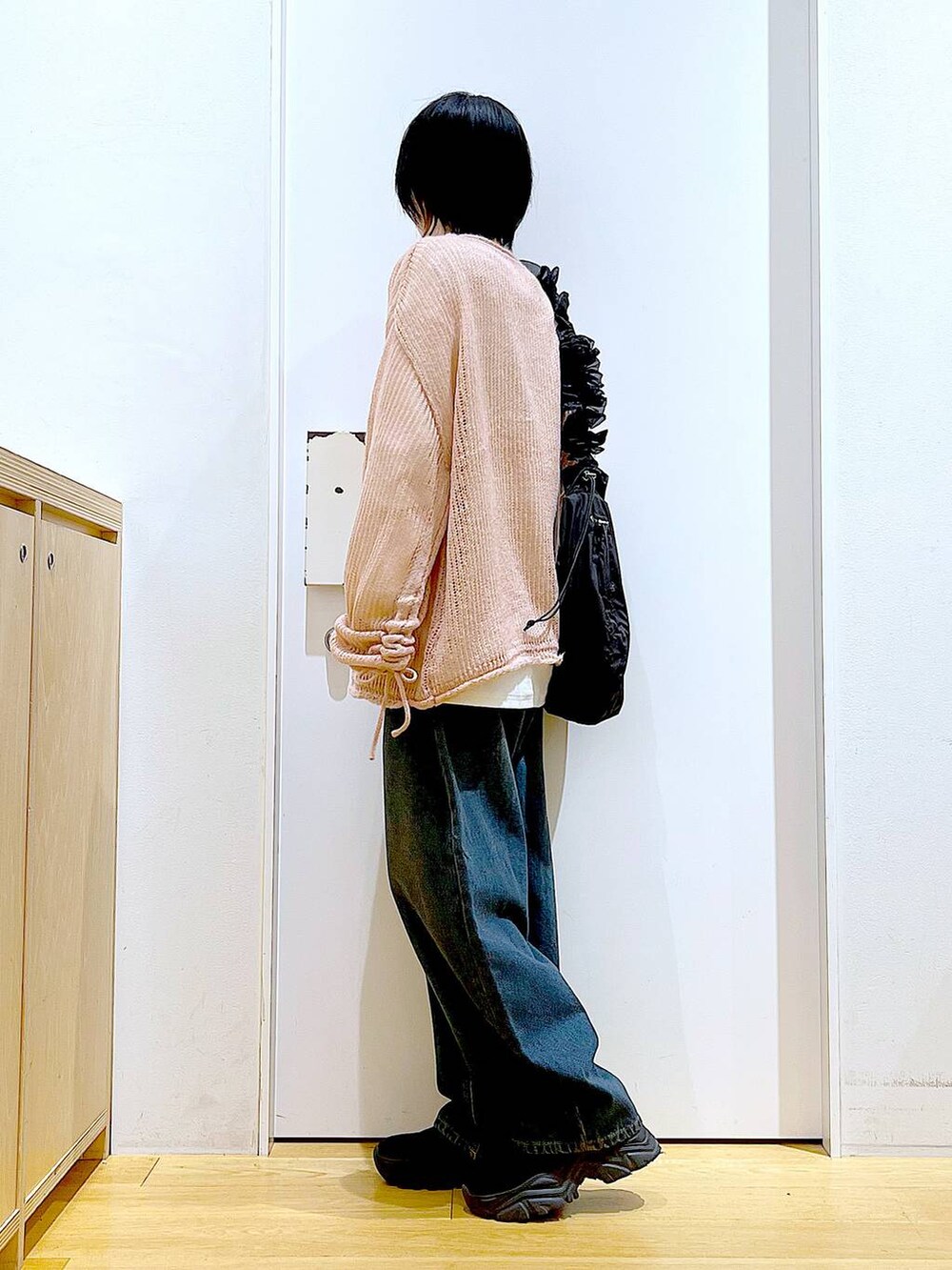 ブラック系のショルダーバッグ、ブラック系のブーツ、ピンク系のニット/セーターを着用したレディースの冬コーディネートの3枚目の写真