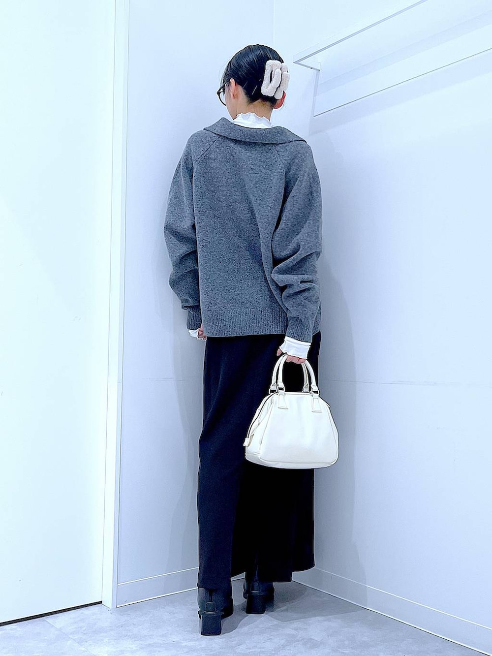 ブラック系のスカート、ブラック系のブーツ、ホワイト系のショルダーバッグを着用したレディースの冬コーディネートの5枚目の写真