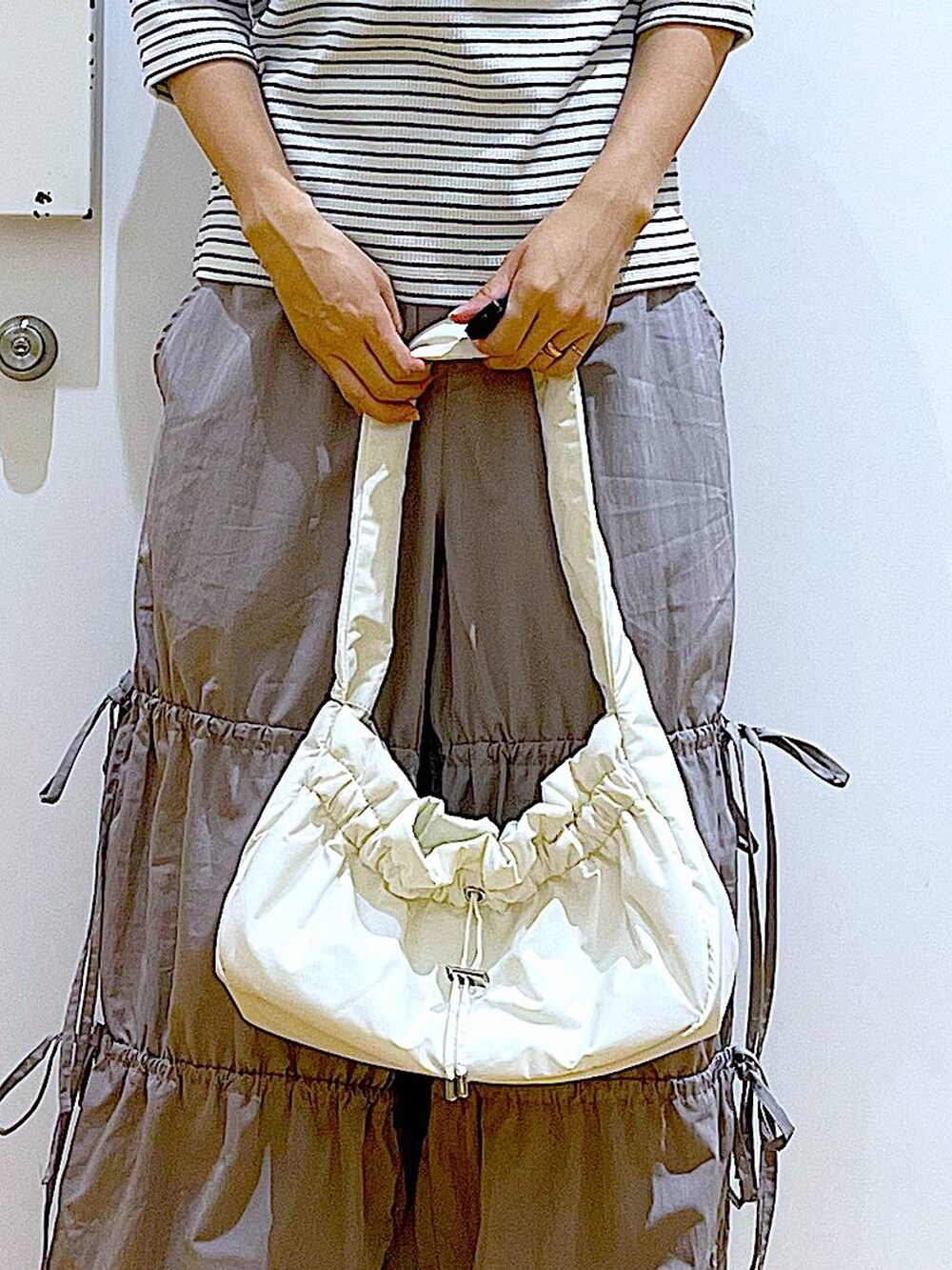 ホワイト系のハンドバッグ、シルバー系のパンプス、グレー系のその他パンツを着用したレディースの秋コーディネートの9枚目の写真