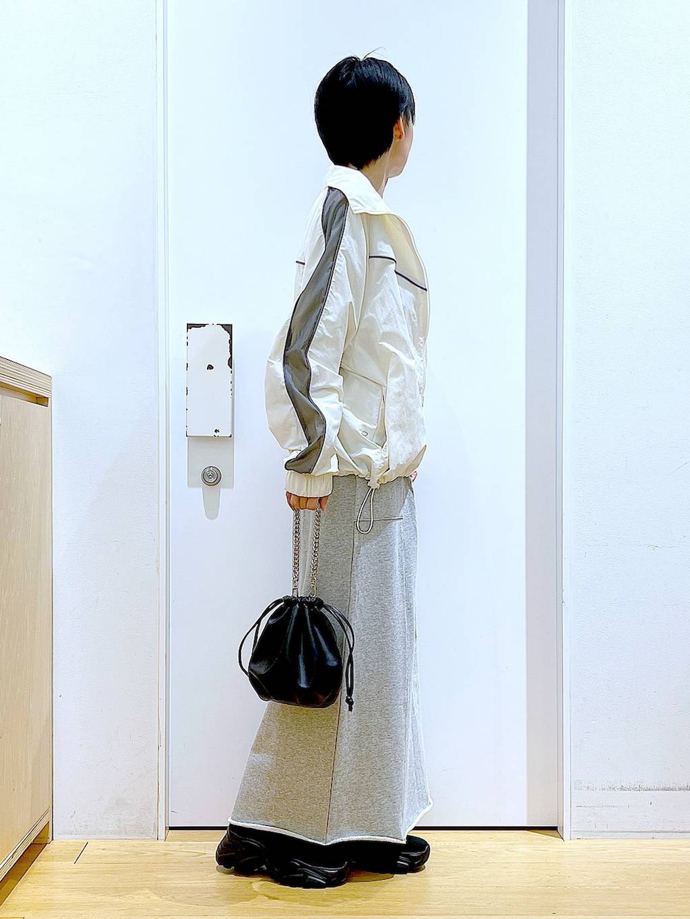 ブラック系のブーツ、ブラック系のショルダーバッグ、グレー系のスカートを着用したレディースの春コーディネートの4枚目の写真