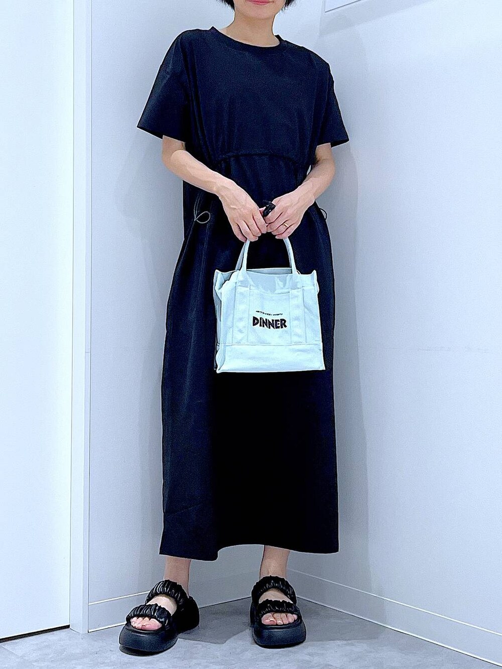 ブラック系のサンダル、ブラック系のワンピース、グリーン系のトートバッグを着用したレディースの夏コーディネートの6枚目の写真