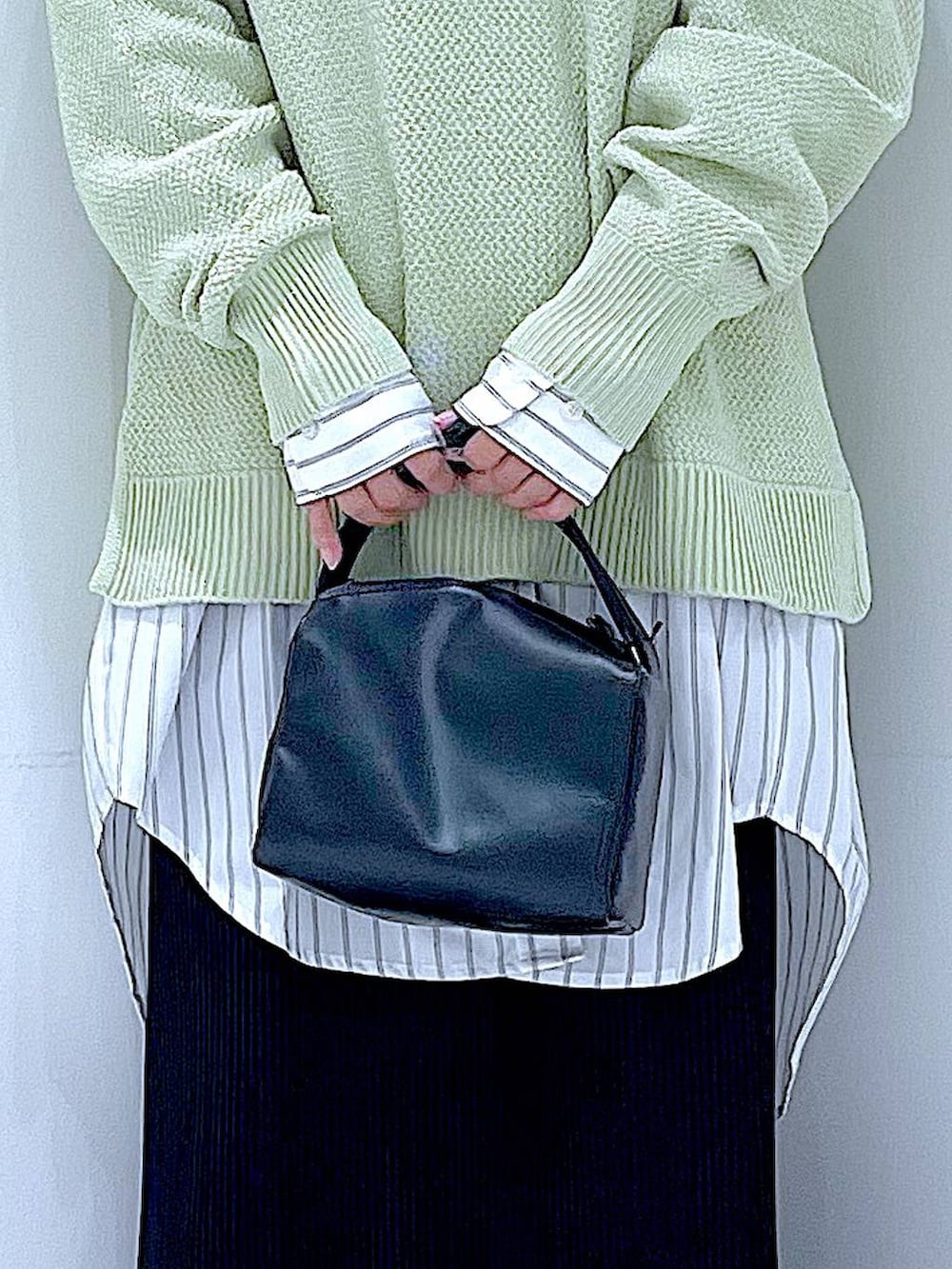 ブラック系のショルダーバッグ、ホワイト系のシャツ/ブラウス、グリーン系のニット/セーターを着用したレディースの春コーディネートの9枚目の写真