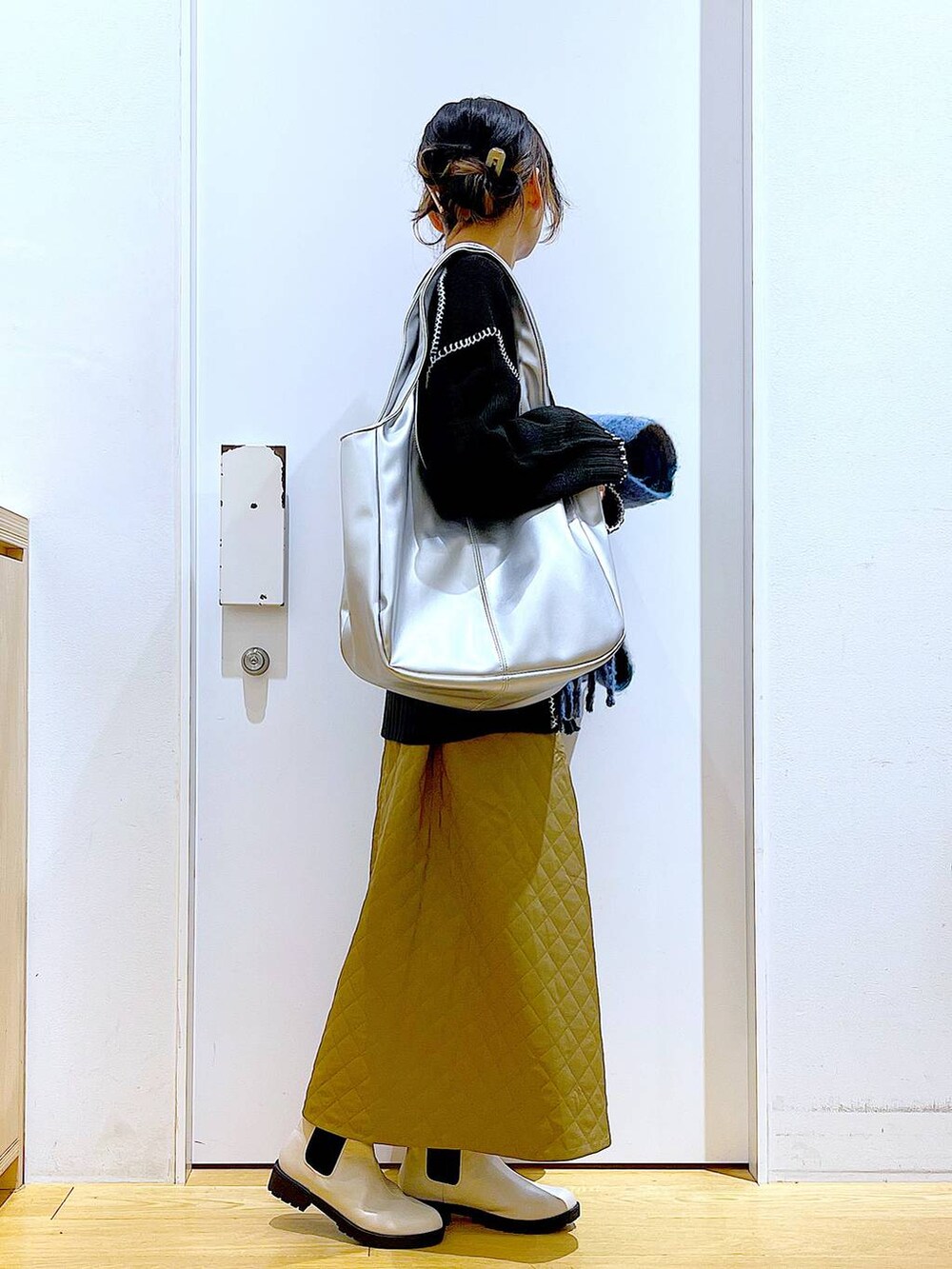 シルバー系のトートバッグ、ベージュ系のブーツ、ブラック系のニット/セーターを着用したレディースの冬コーディネートの4枚目の写真