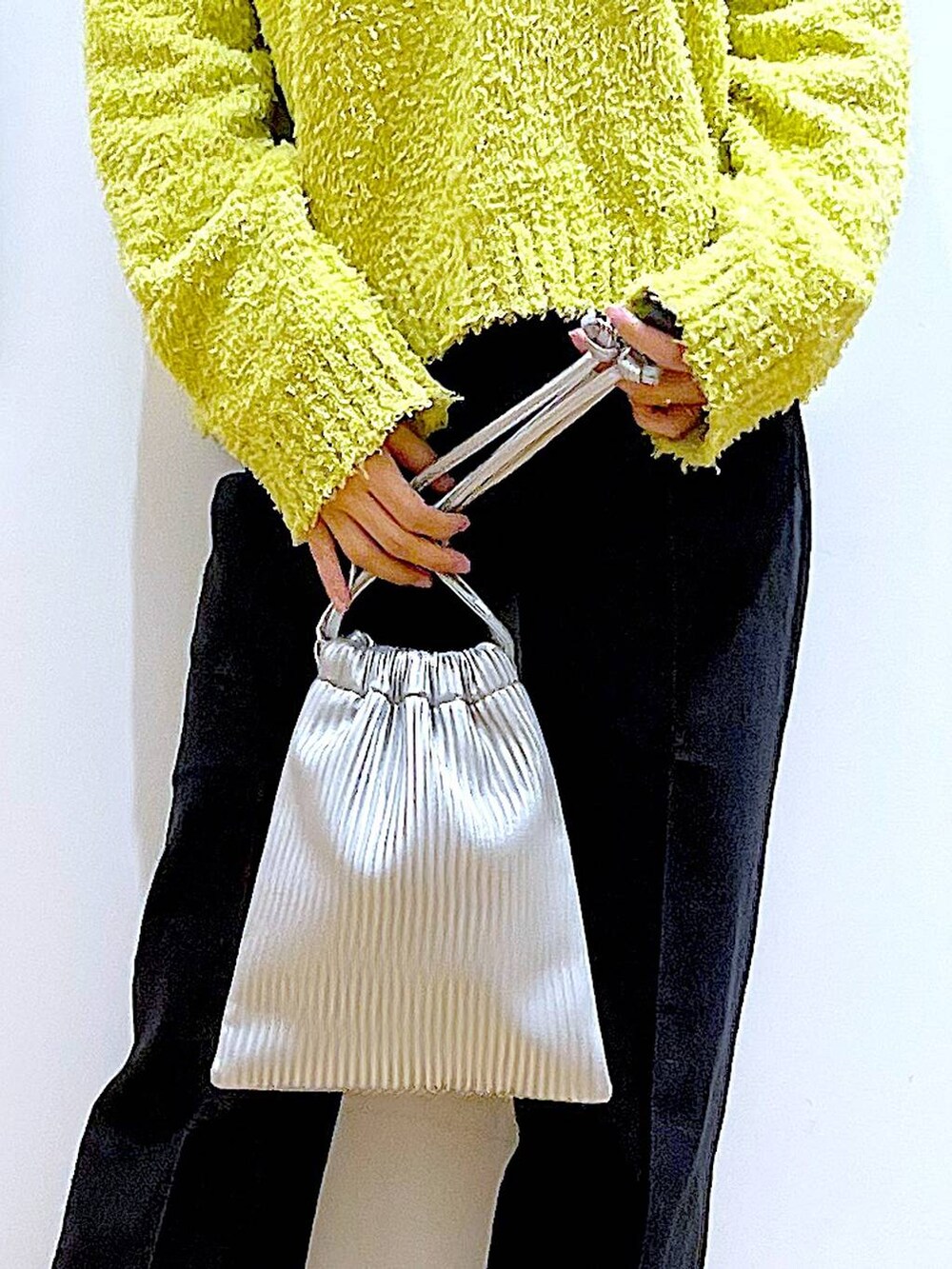 グリーン系のニット/セーター、グレー系のデニムパンツ、シルバー系のショルダーバッグを着用したレディースの冬コーディネートの9枚目の写真