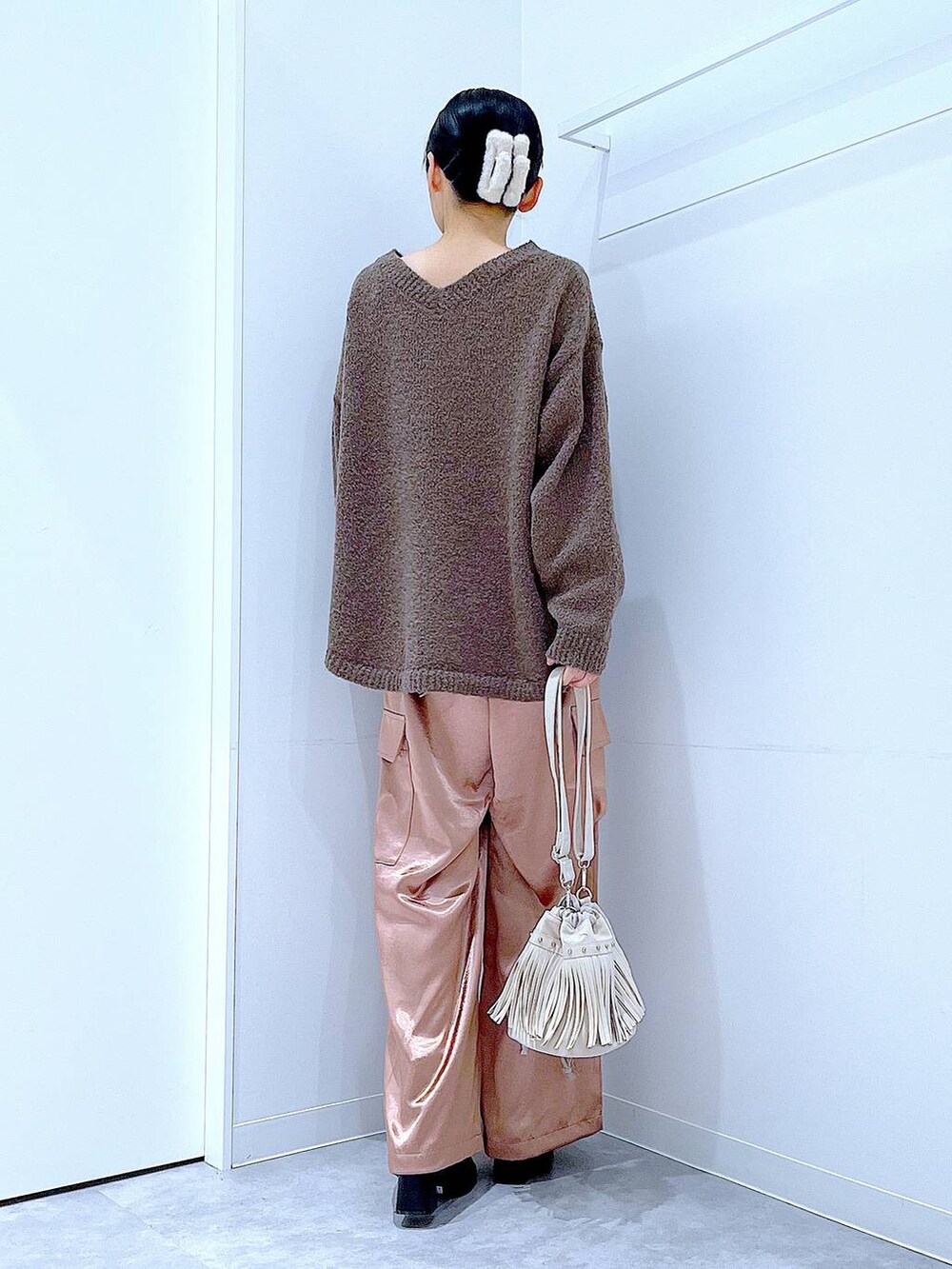 ブラウン系のニット/セーター、ブラック系のブーツ、ホワイト系のショルダーバッグを着用したレディースの冬コーディネートの5枚目の写真