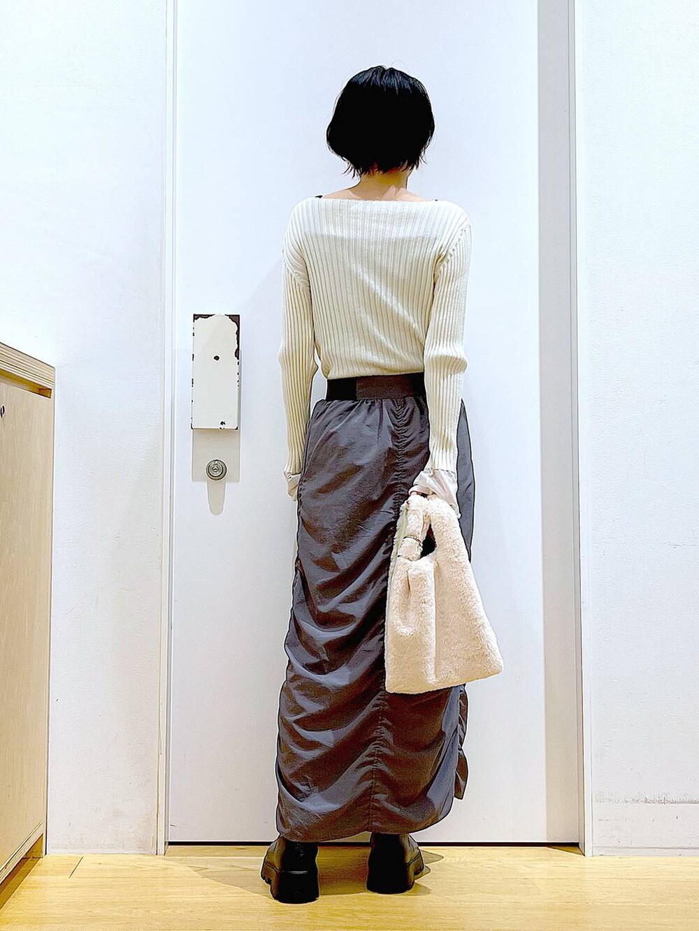 ホワイト系のニット/セーター、ホワイト系のショルダーバッグ、ブラック系のブーツを着用したレディースの秋コーディネートの5枚目の写真