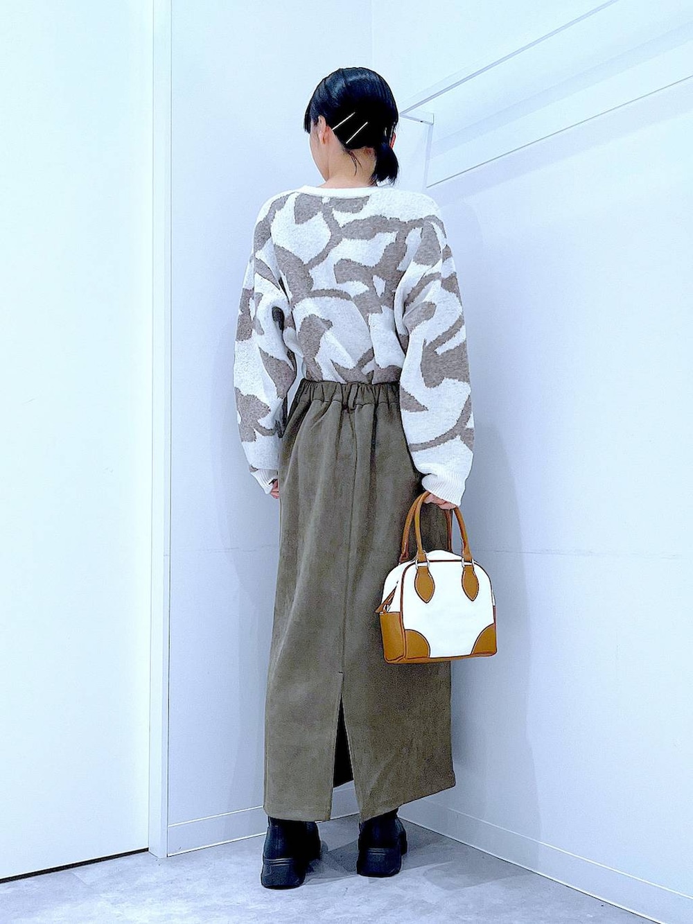 ブラック系のブーツ、ホワイト系のハンドバッグ、グリーン系のスカートを着用したレディースの秋コーディネートの5枚目の写真