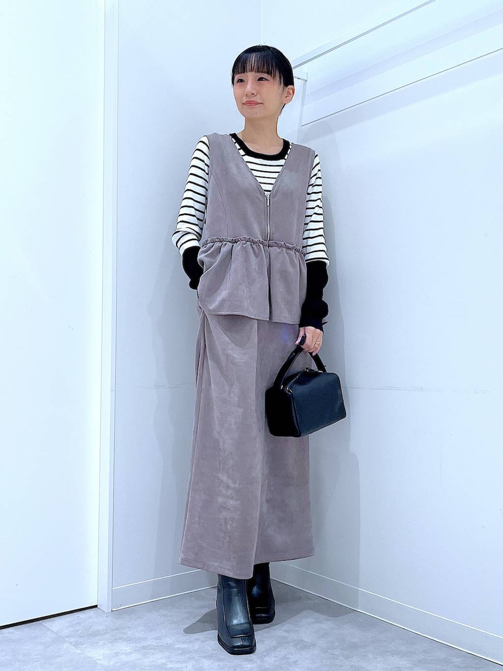 ブラック系のブーツ、グレー系のワンピース、ブラック系のショルダーバッグを着用したレディースの冬コーディネートの2枚目の写真