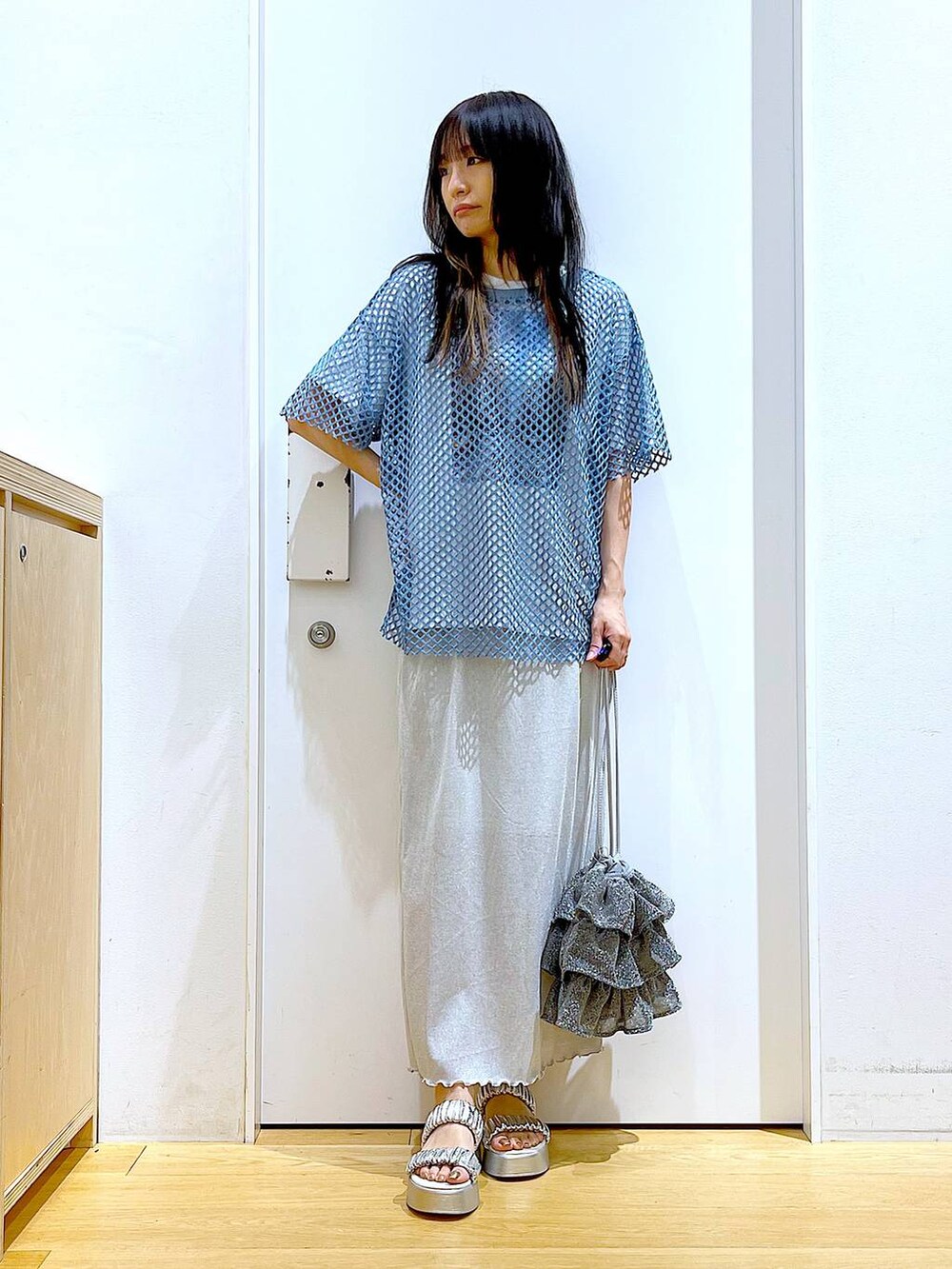 グレー系のスカート、シルバー系のショルダーバッグ、ホワイト系のTシャツ/カットソーを着用したレディースの夏コーディネートの2枚目の写真