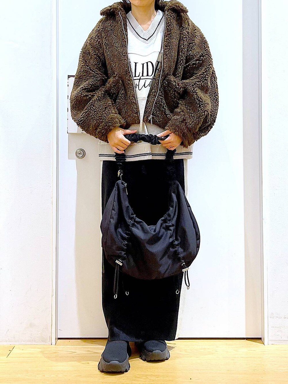 ブラック系のスカート、ブラック系のショルダーバッグ、ブラック系のブーツを着用したレディースの冬コーディネートの6枚目の写真