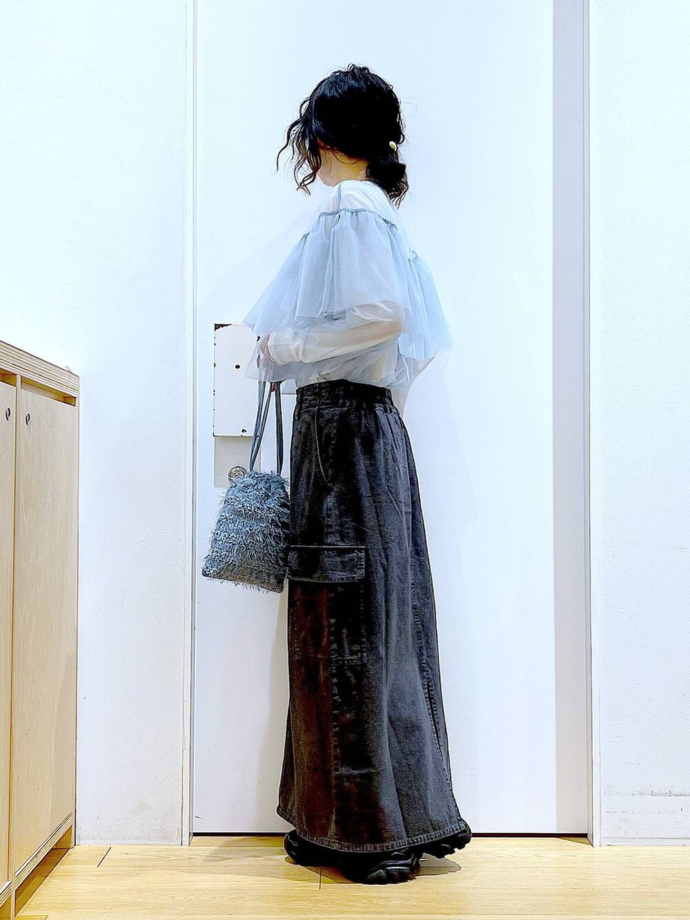 グレー系のデニムスカート、ブラック系のスニーカー、ブルー系のその他トップスを着用したレディースの春コーディネートの3枚目の写真