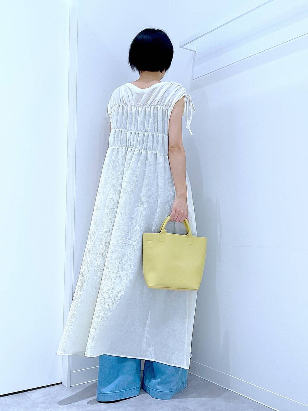 ブラック系のサンダル、ブルー系のデニムパンツ、ベージュ系のワンピースを着用したレディースの夏コーディネートの5枚目の写真