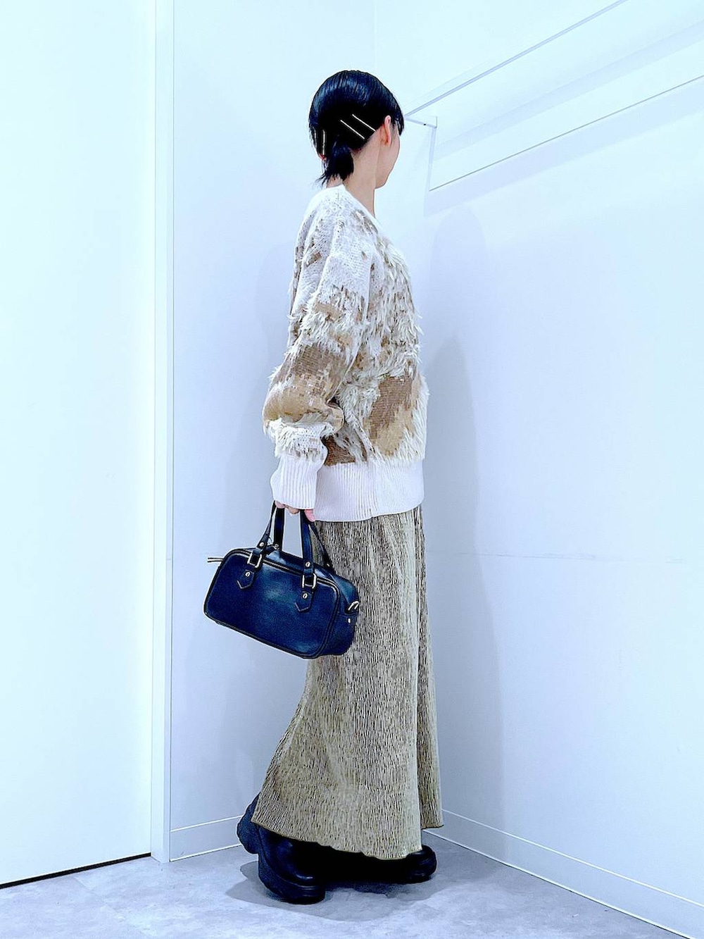 ブラック系のブーツ、ブラック系のショルダーバッグ、グリーン系のスカートを着用したレディースの冬コーディネートの4枚目の写真