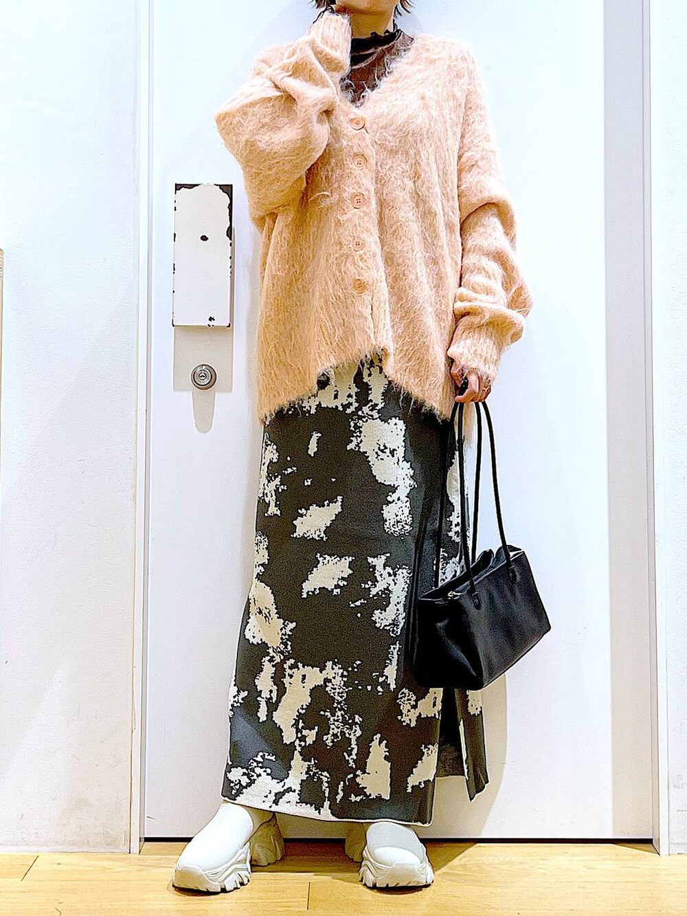 グレー系のスカート、ブラック系のトートバッグ、ピンク系のカーディガン/ボレロを着用したレディースの秋コーディネートの6枚目の写真