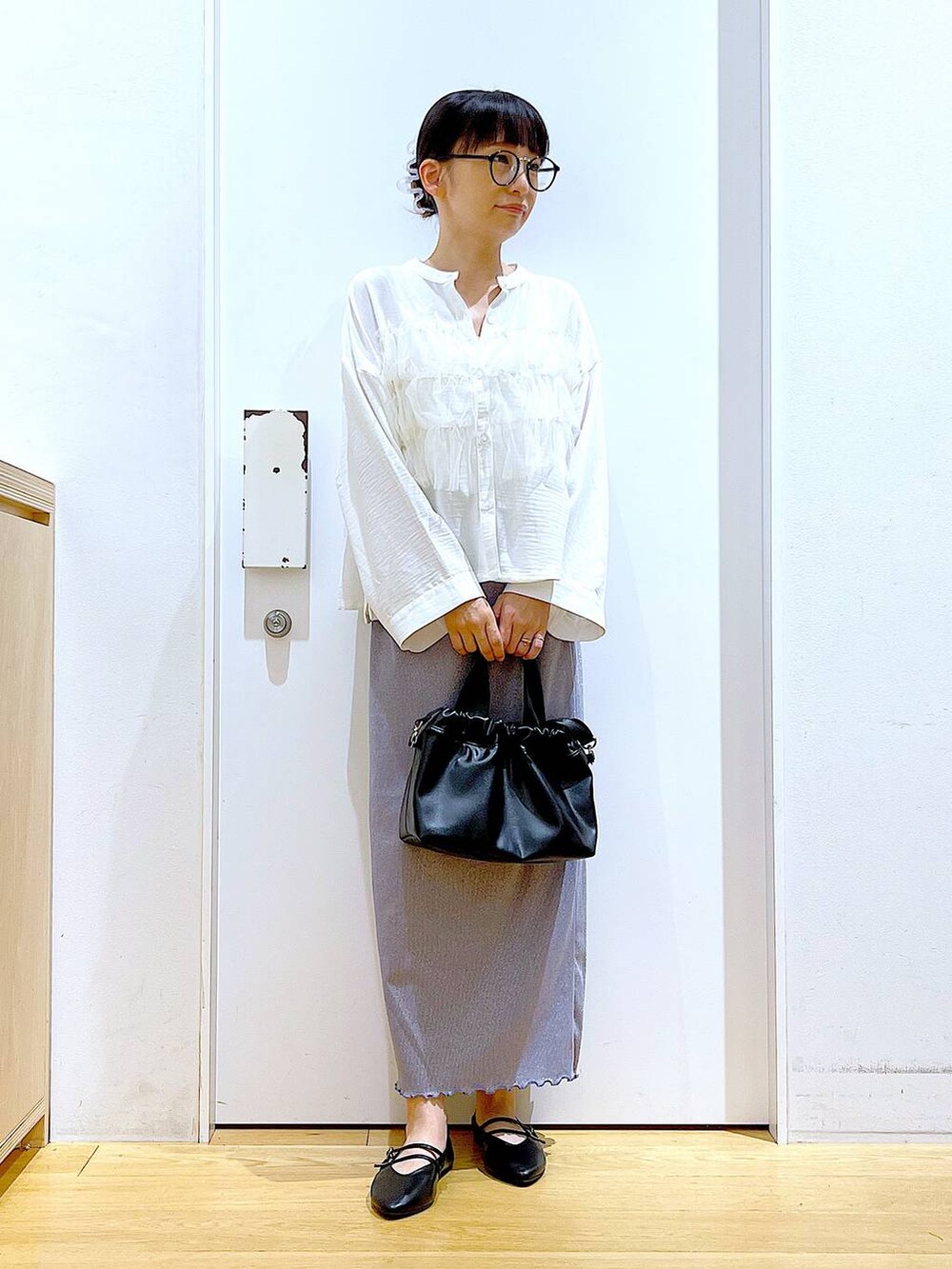 パープル系のスカート、ブラック系のショルダーバッグ、ブラック系のパンプスを着用したレディースの秋コーディネートの2枚目の写真