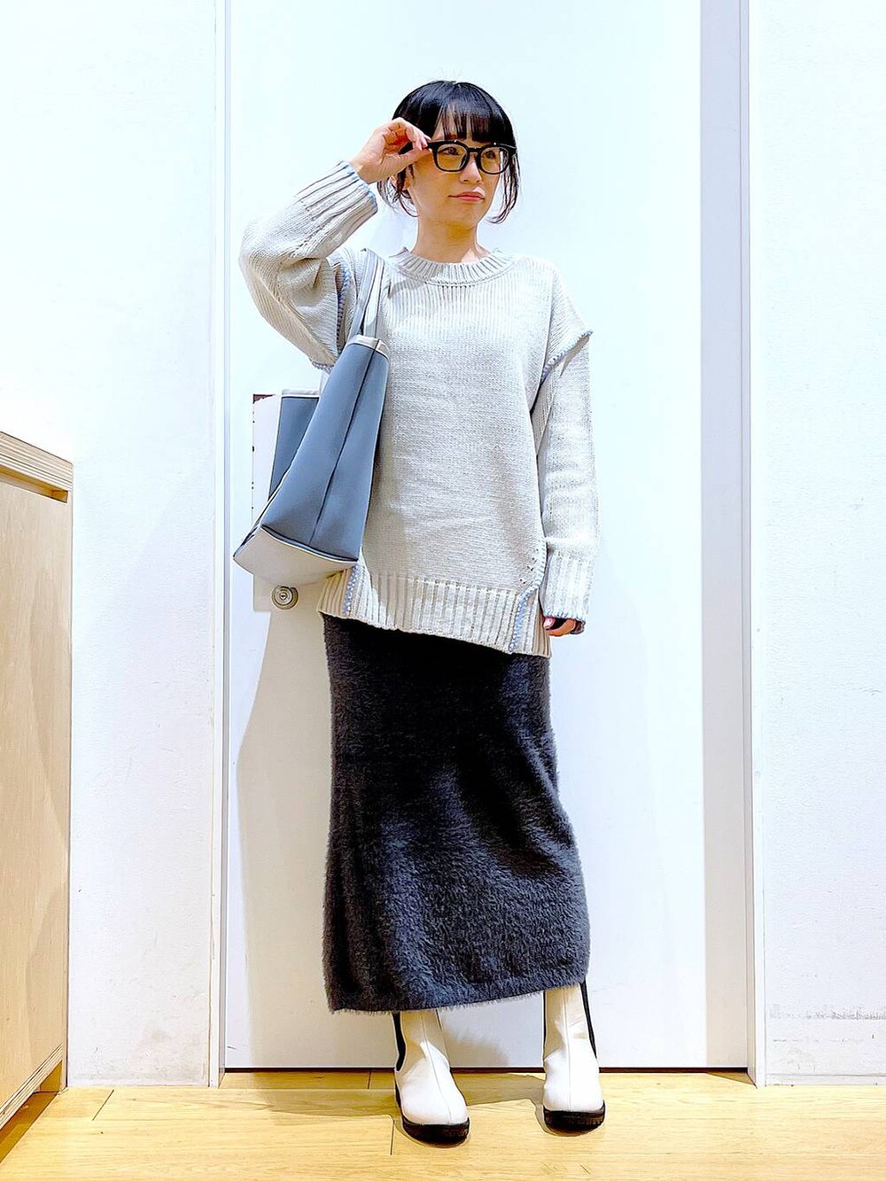 グレー系のトートバッグ、ベージュ系のブーツ、グレー系のスカートを着用したレディースの冬コーディネートの2枚目の写真