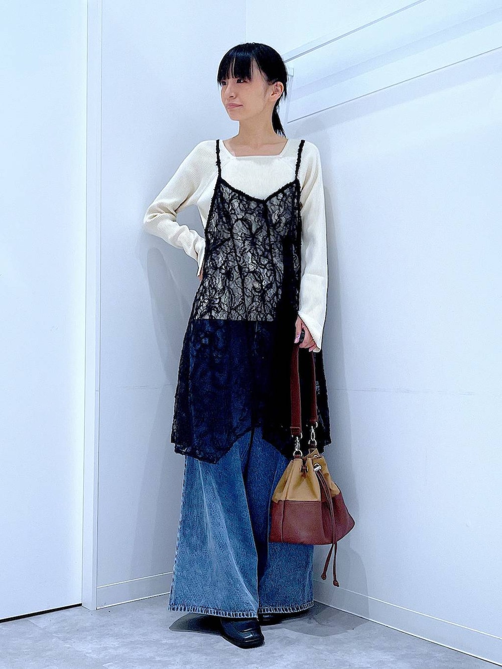 ベージュ系のニット/セーター、ブルー系のデニムパンツ、ベージュ系のショルダーバッグを着用したレディースの秋コーディネートの2枚目の写真