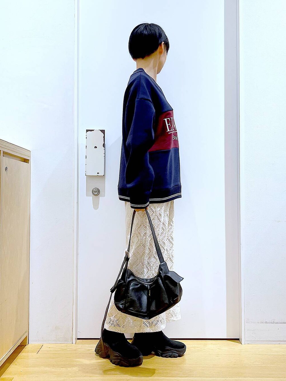 ブラック系のブーツ、ホワイト系のスカート、ブラック系のショルダーバッグを着用したレディースの冬コーディネートの4枚目の写真