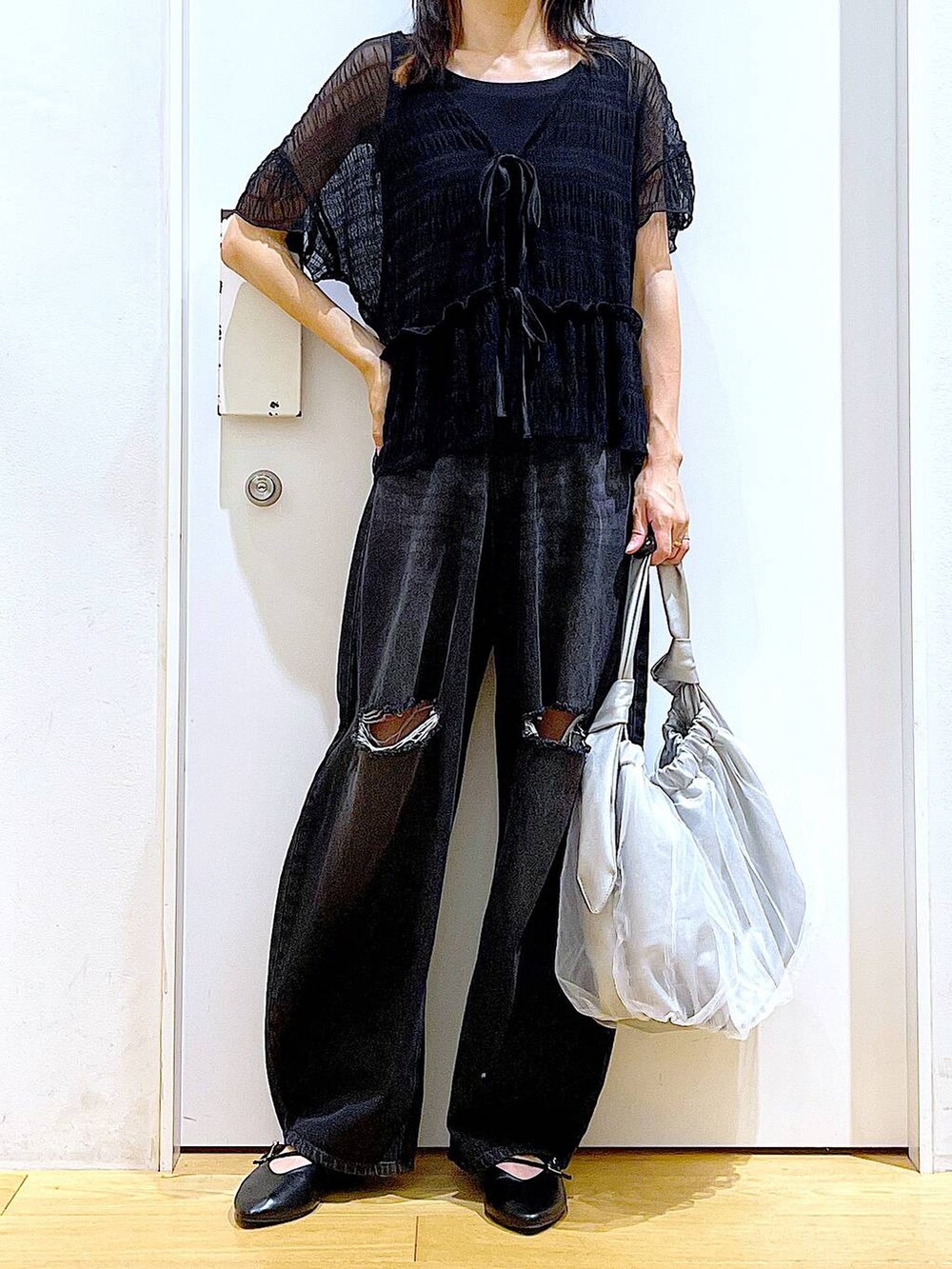 シルバー系のトートバッグ、ブラック系のデニムパンツ、ブラック系のカーディガン/ボレロを着用したレディースの秋コーディネートの6枚目の写真