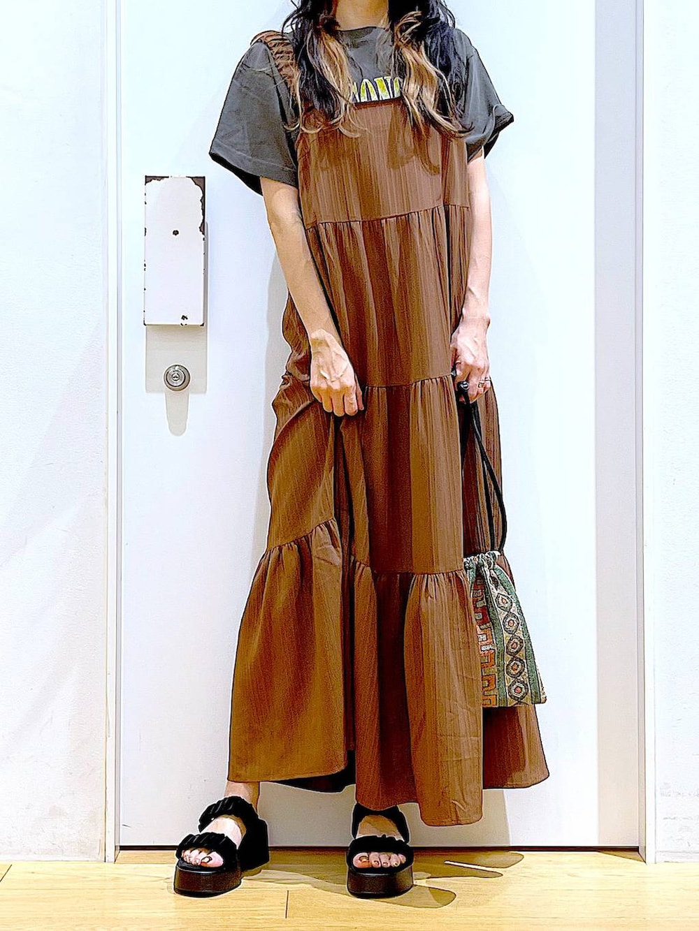 ブラウン系のショルダーバッグ、ブラック系のサンダル、グレー系のTシャツ/カットソーを着用したレディースの夏コーディネートの6枚目の写真