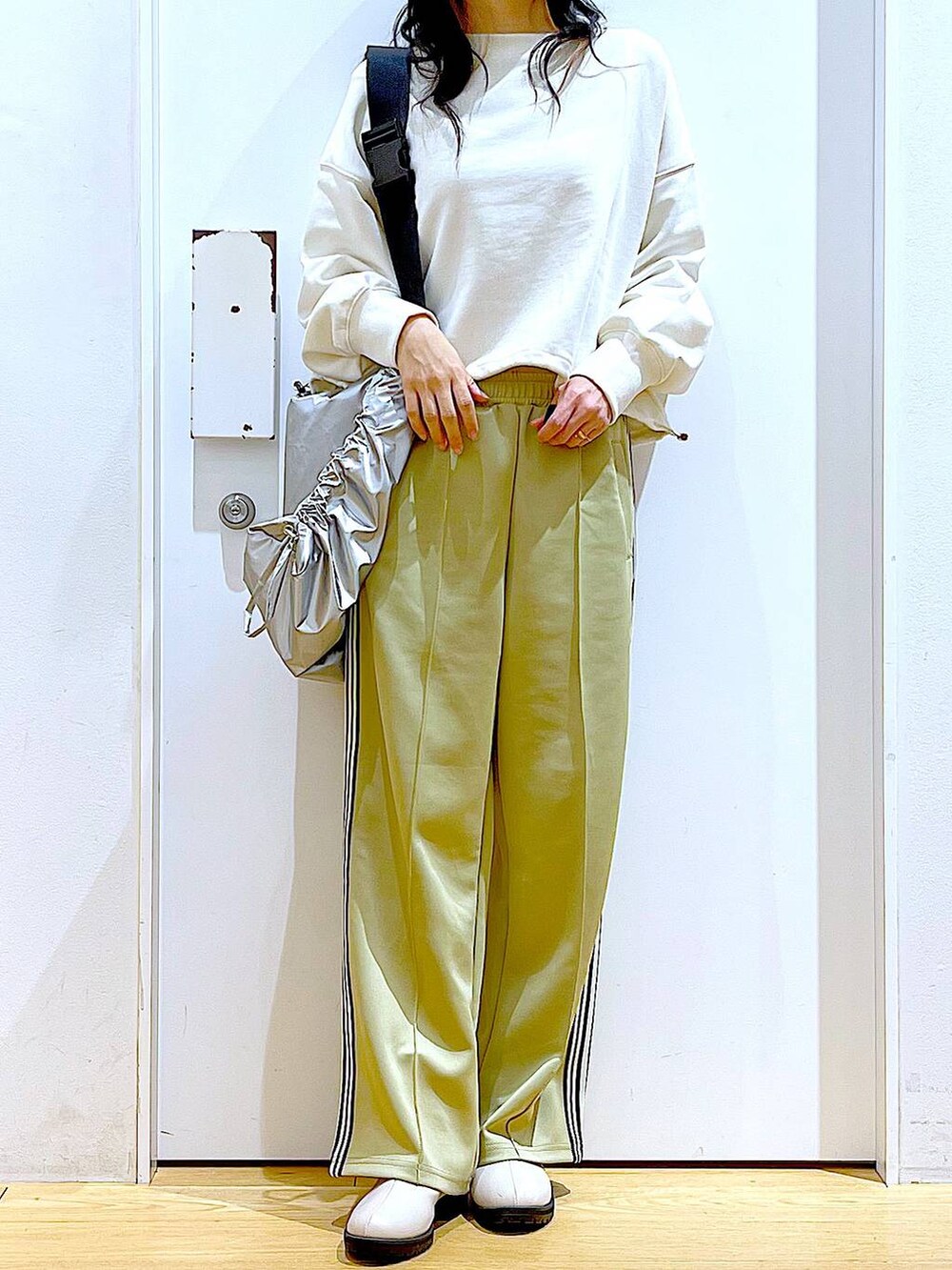 ホワイト系のスウェット、ベージュ系のブーツ、シルバー系のショルダーバッグを着用したレディースの春コーディネートの6枚目の写真