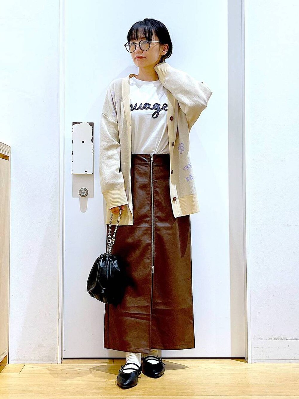 ブラウン系のスカート、ブラック系のショルダーバッグ、ブラック系のパンプスを着用したレディースの秋コーディネートの2枚目の写真