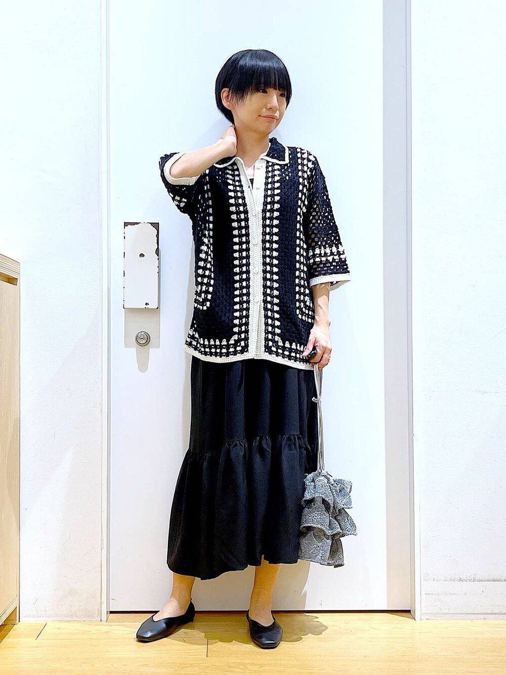 シルバー系のショルダーバッグ、ブラック系のパンプス、ブラック系のワンピースを着用したレディースの春コーディネートの2枚目の写真