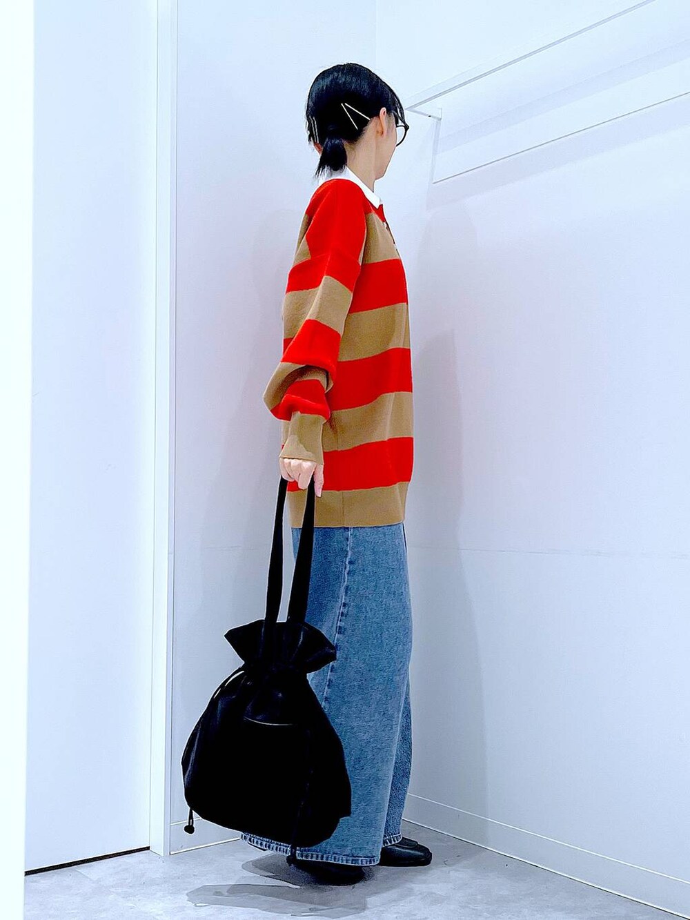 ブラック系のトートバッグ、レッド系のニット/セーター、ブルー系のデニムパンツを着用したレディースの冬コーディネートの4枚目の写真