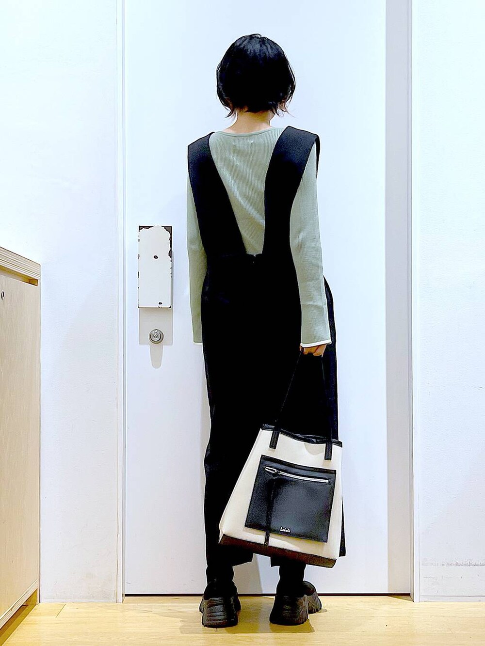 グリーン系のニット/セーター、ブラック系のブーツ、ブラック系のサロペット/オーバーオールを着用したレディースの冬コーディネートの5枚目の写真