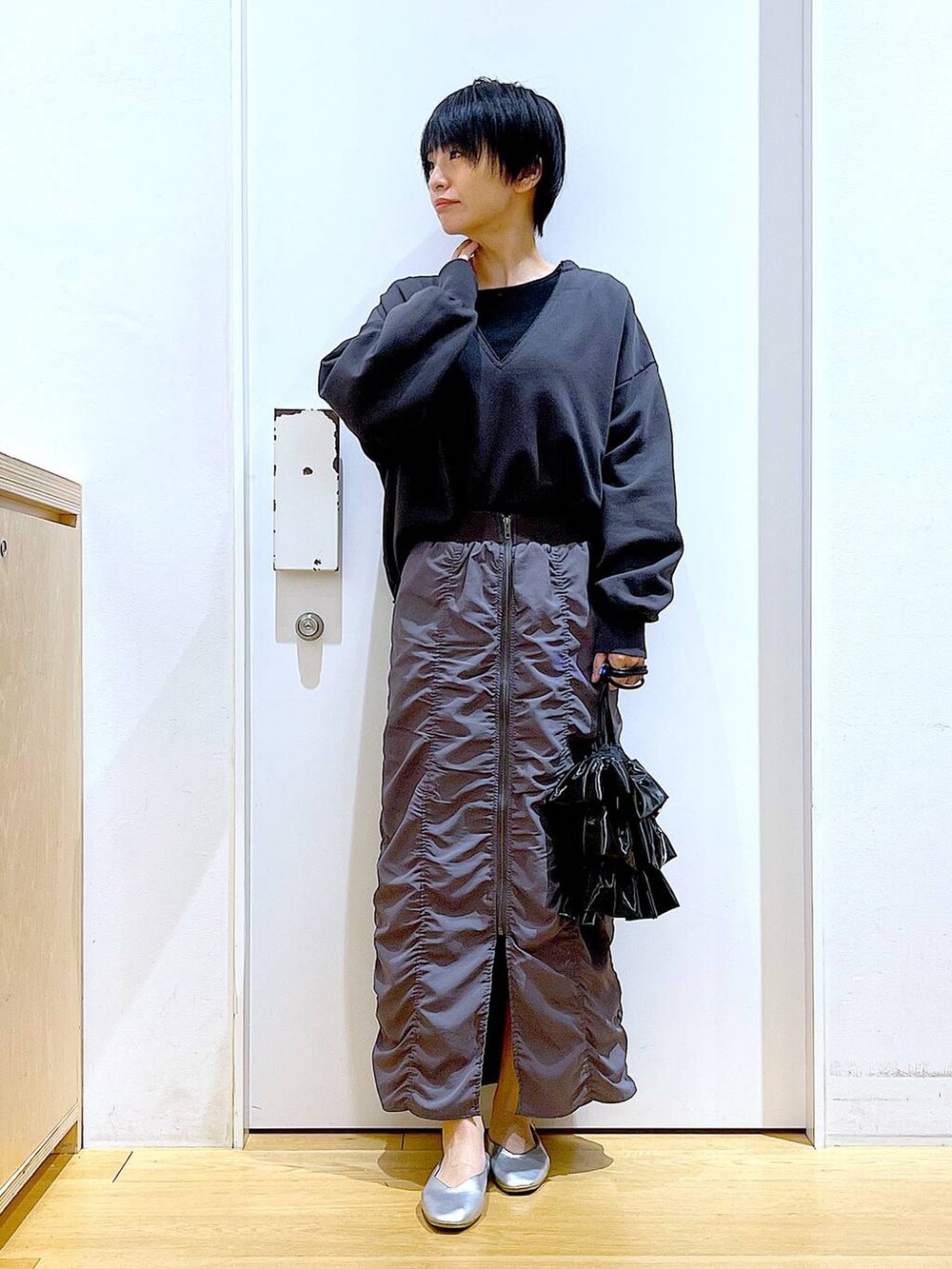 グレー系のスカート、ブラック系のショルダーバッグ、シルバー系のパンプスを着用したレディースの春コーディネートの2枚目の写真