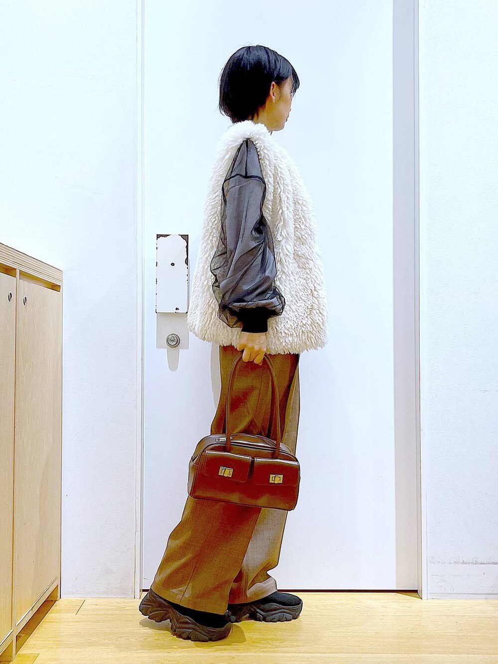 ベージュ系のベスト、ブラウン系のハンドバッグ、ブラック系のブーツを着用したレディースの冬コーディネートの4枚目の写真