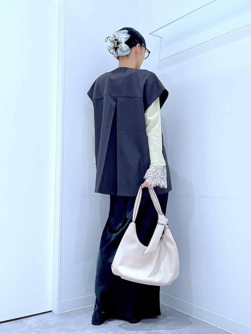 ブラック系のスカート、グレー系のベスト、ブラック系のローファーを着用したレディースの春コーディネートの5枚目の写真