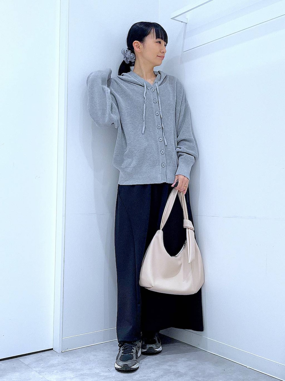 ホワイト系のショルダーバッグ、ブラック系のスカート、グレー系のカーディガン/ボレロを着用したレディースの春コーディネートの2枚目の写真