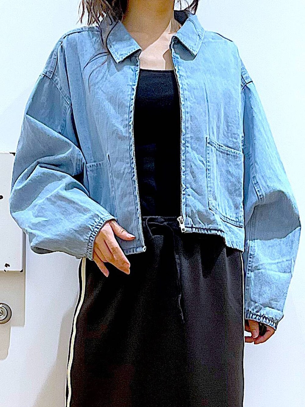 ブルー系のデニムジャケット、ブラック系のスカート、ブラック系のスニーカーを着用したレディースの春コーディネートの7枚目の写真