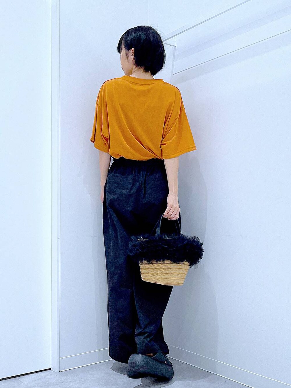 ベージュ系のショルダーバッグ、ブラック系のサンダル、オレンジ系のTシャツ/カットソーを着用したレディースの夏コーディネートの5枚目の写真