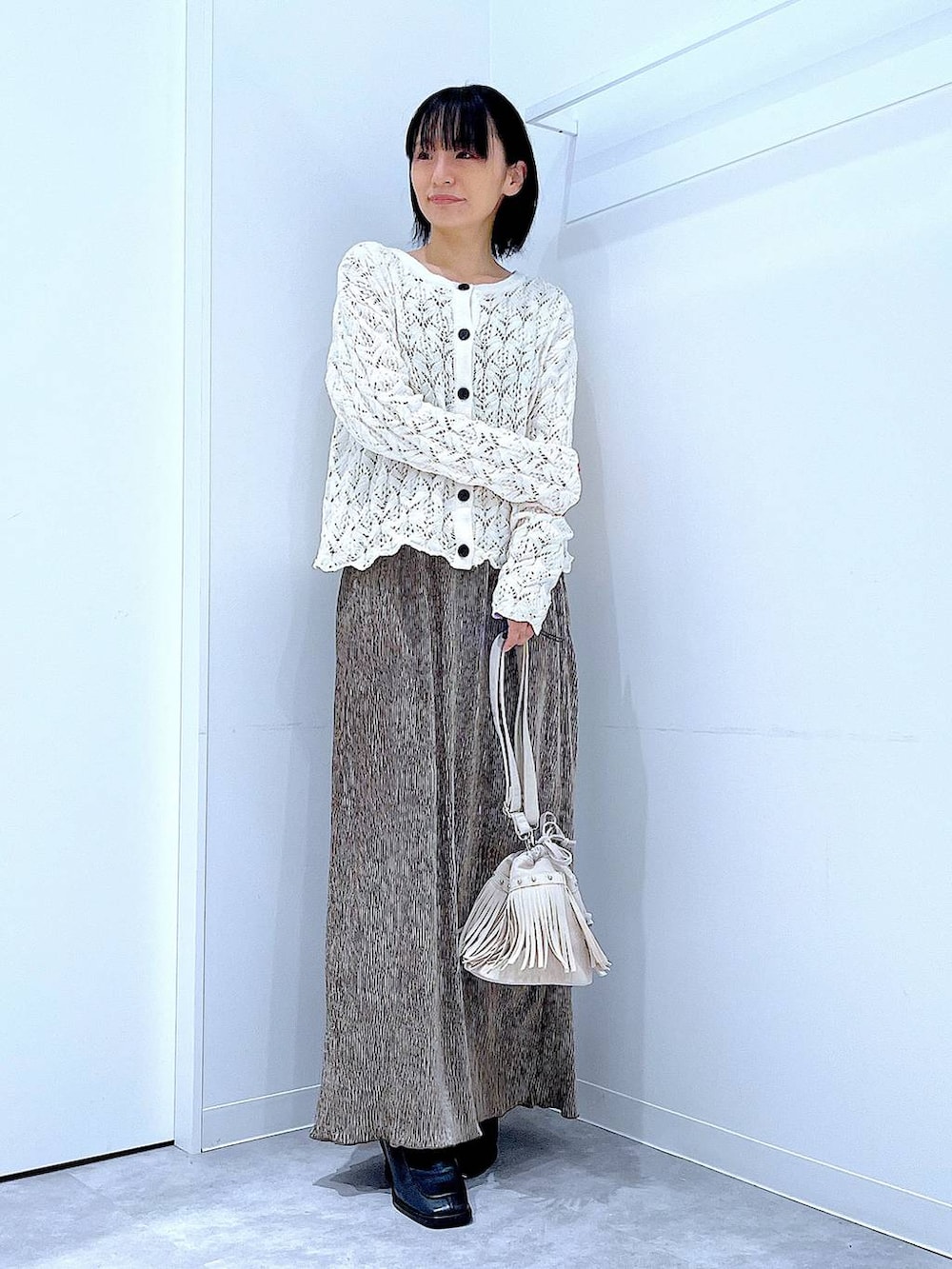 ブラック系のブーツ、ホワイト系のショルダーバッグ、ベージュ系のカーディガン/ボレロを着用したレディースの冬コーディネートの2枚目の写真