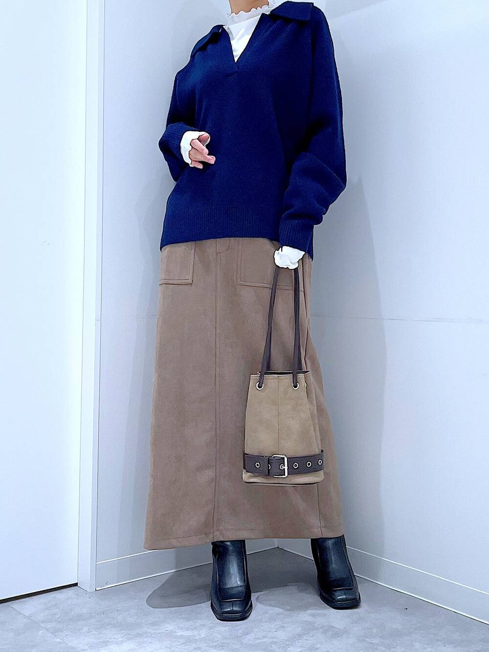 ブラック系のブーツ、ブラウン系のスカート、ベージュ系のハンドバッグを着用したレディースの冬コーディネートの6枚目の写真