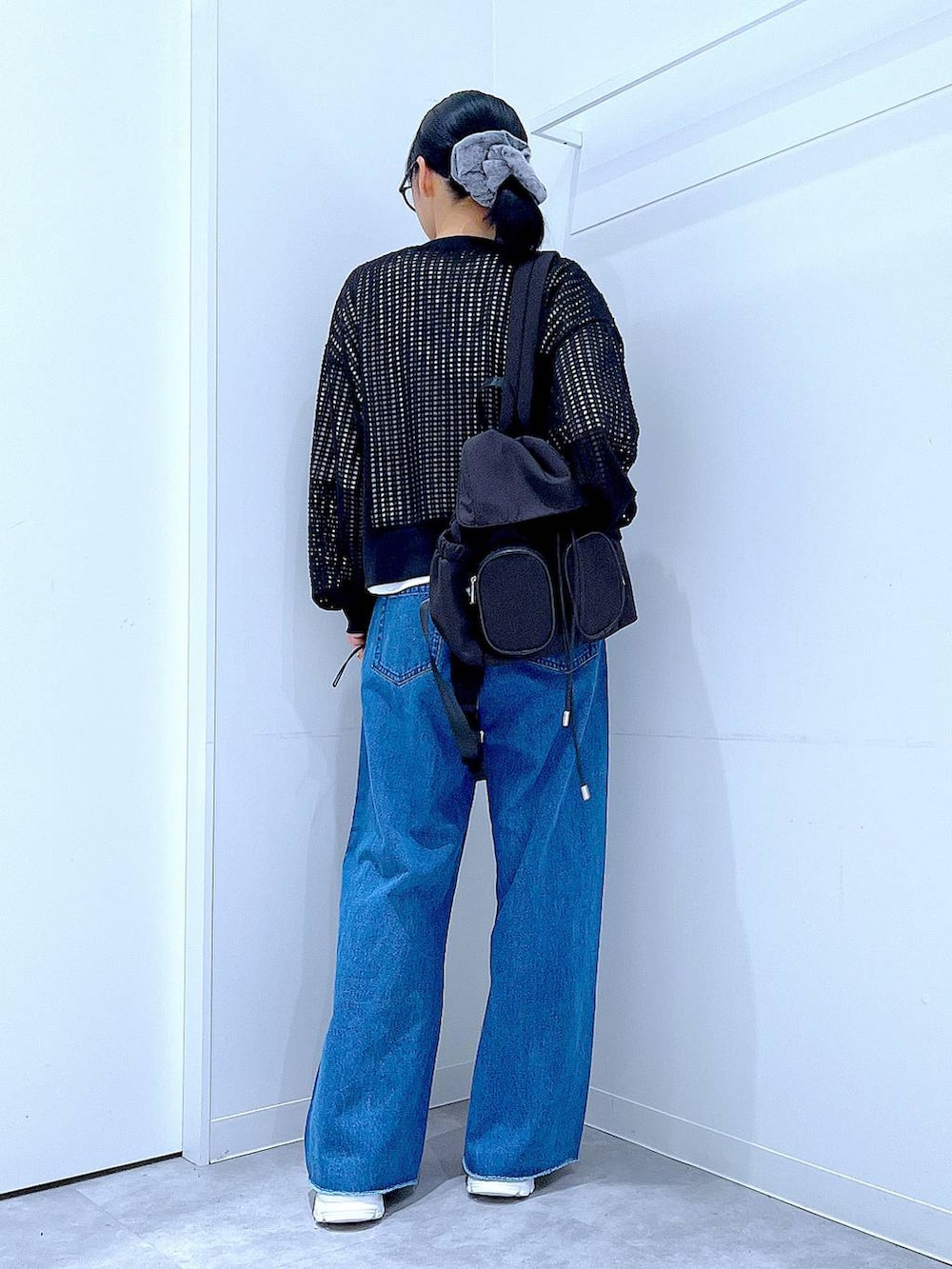 ブラック系のバックパック/リュック、ホワイト系のスニーカー、ブルー系のデニムパンツを着用したレディースの春コーディネートの5枚目の写真
