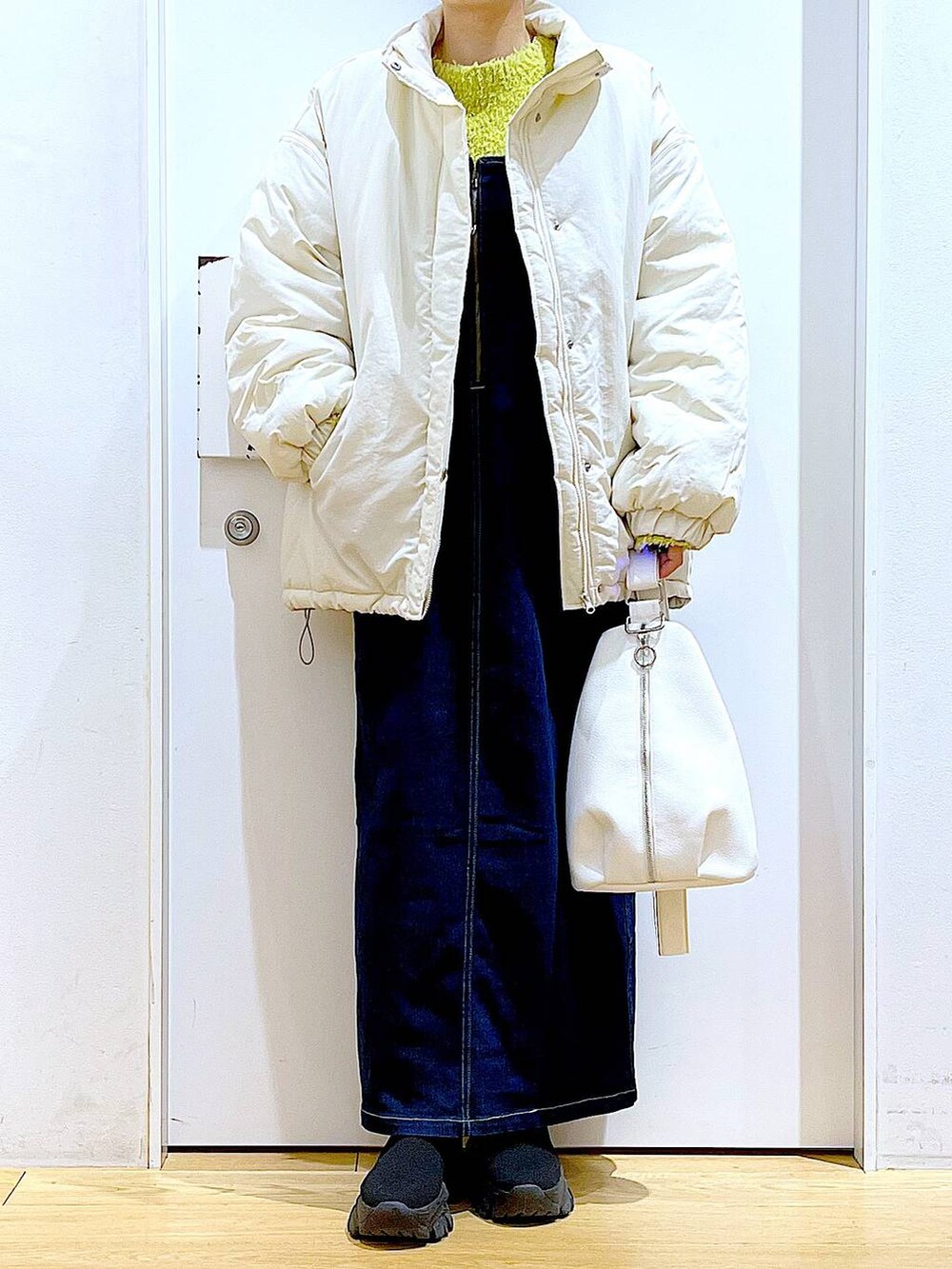 グリーン系のニット/セーター、ブルー系のジャンパースカート、ホワイト系のボディバッグ/ウエストポーチを着用したレディースの冬コーディネートの6枚目の写真