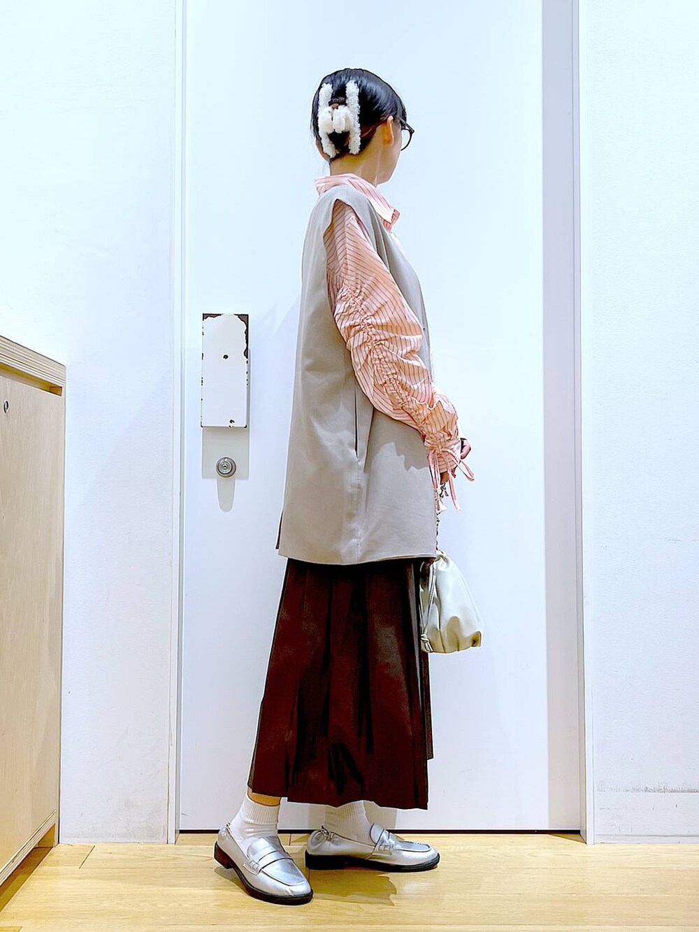 ベージュ系のショルダーバッグ、シルバー系のローファー、ベージュ系のベストを着用したレディースの秋コーディネートの4枚目の写真