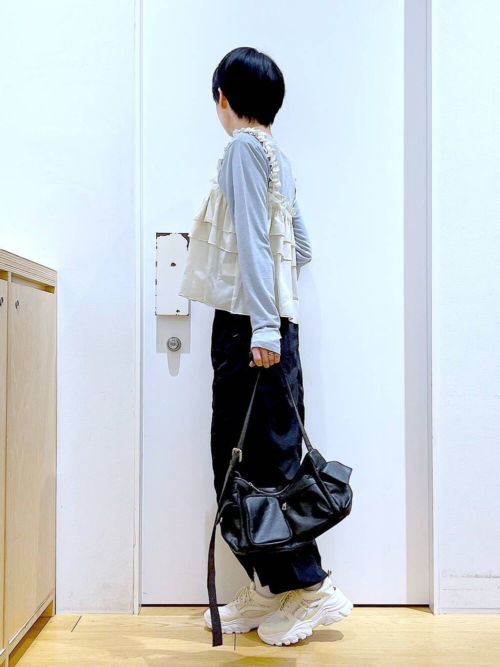 ブラック系のスカート、ブラック系のショルダーバッグ、ホワイト系のスニーカーを着用したレディースの春コーディネートの3枚目の写真