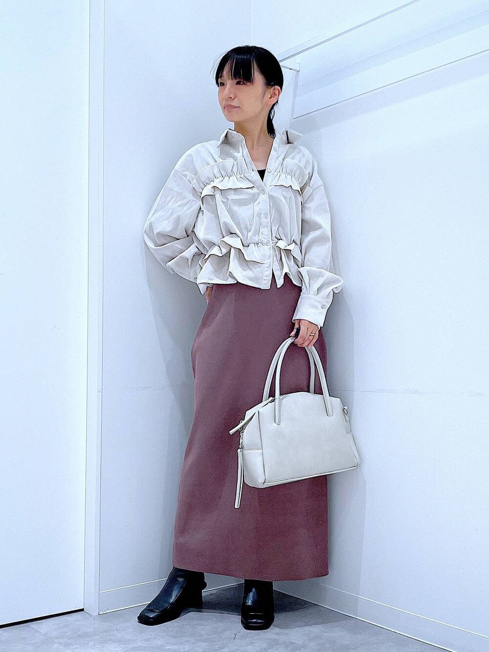 グレー系のボストンバッグ、ブラック系のブーツ、ベージュ系のシャツ/ブラウスを着用したレディースの秋コーディネートの2枚目の写真